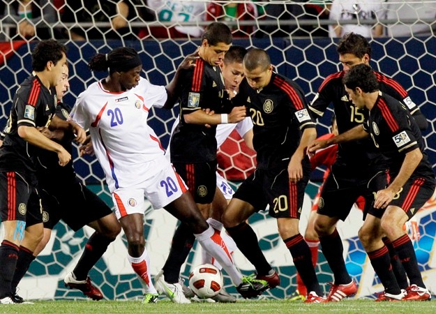 Obranca Kostariky Dennis Marshall v súboji s mexickou obranou